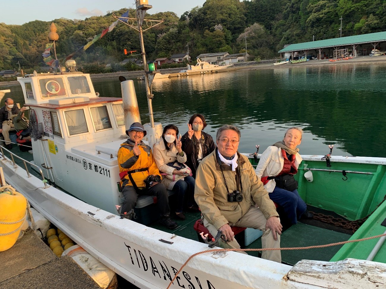 【宮津湾の西の山々に沈もうとする夕陽を洋上鑑賞するためTIDANESIA号で出港するツアーメンバーたち】